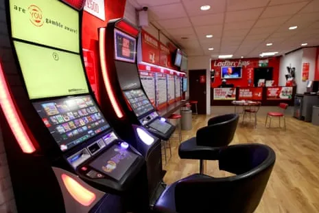 Interior de un local de apuestas de Ladbrokes con terminales de juego y zona de asientos
